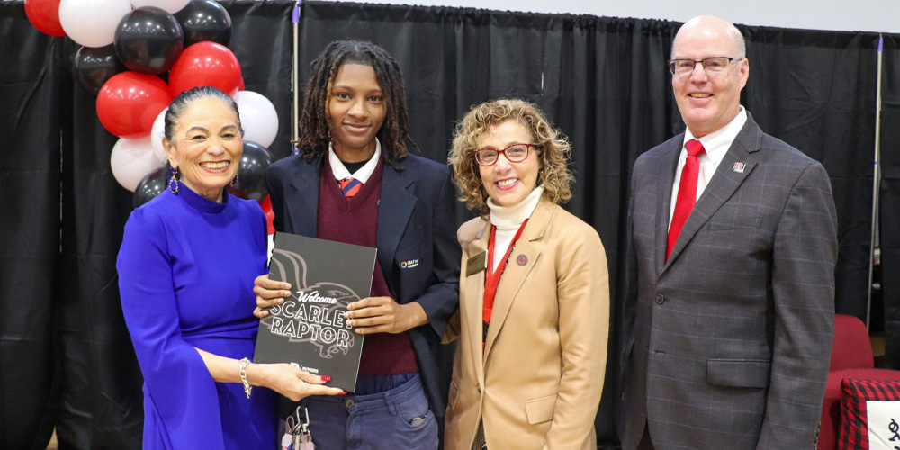 Administrators posing for a photo with a LEAP student holding their acceptance packet to Rutgers